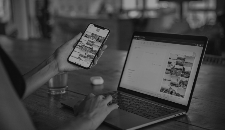 My Digital Solutions – The Global Tech Hub® UK: Person working at a wooden desk with smartphone and laptop displaying synchronized photo galleries, symbolizing digital media management, image editing, cross-device workflow, and modern content creation solutions.