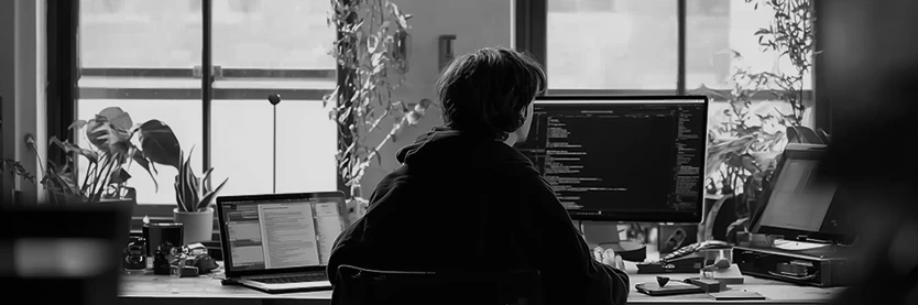 My Digital Solutions staff member working on Laravel web development at a modern office desk with multiple screens and natural lighting.