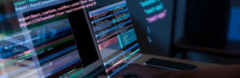 Modern web developer working on React application code across multiple screens, representing advanced front-end development.